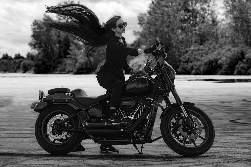 A Siren riding her Harley Low Rider S, long hair streaming in the wind.